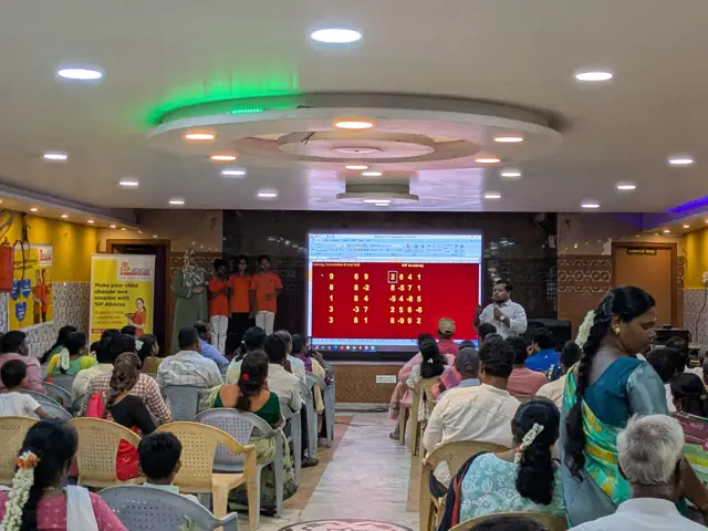 Students solving mental maths sums shown on a big screen in front of parents