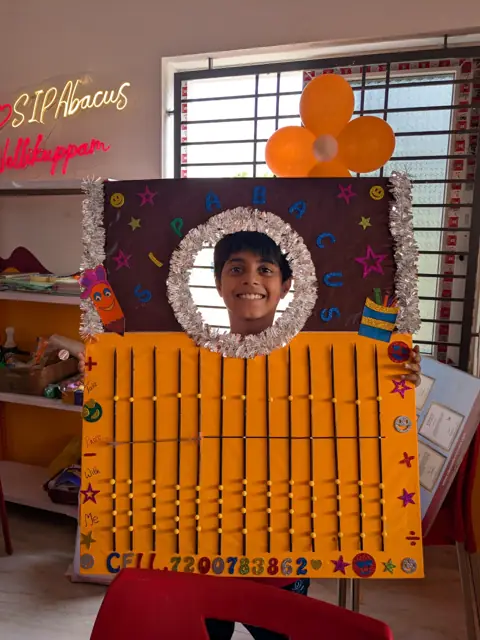 A smiling student with the giant abacus display at SIP Abacus Nellikuppam